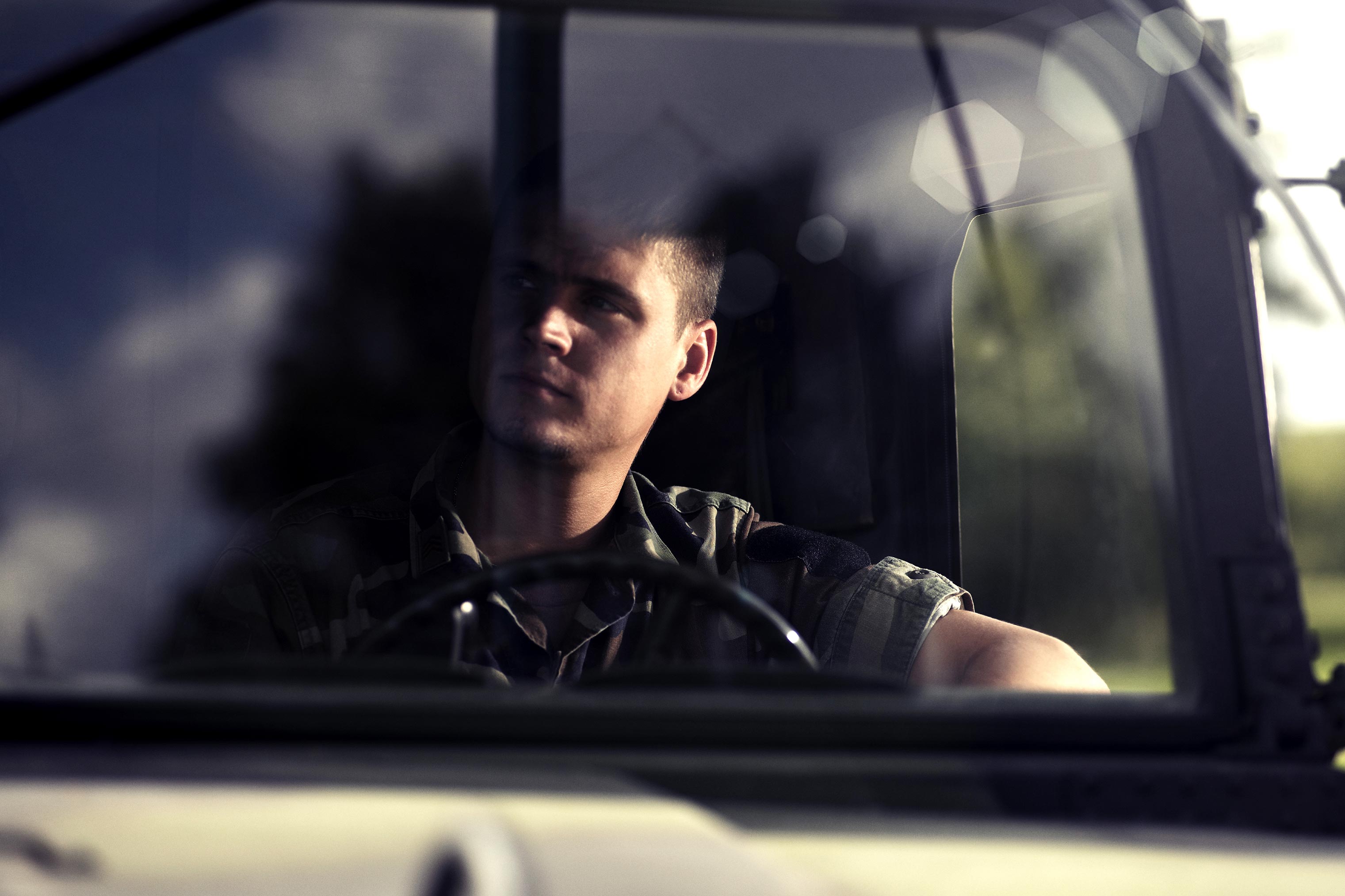 Soldier behind windscreen of red cross army ambulance.