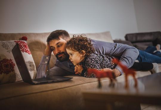 Father and daughter watching videos on laptop