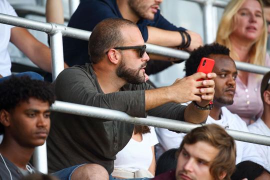 Man with phone watching match