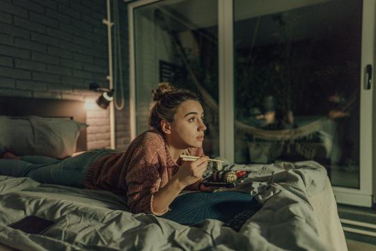 woman eating sushi while watching tv