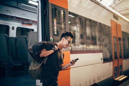 Man getting off train watching phone