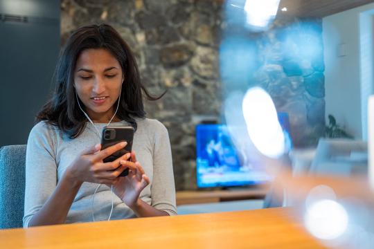 woman watching news on phone and tv