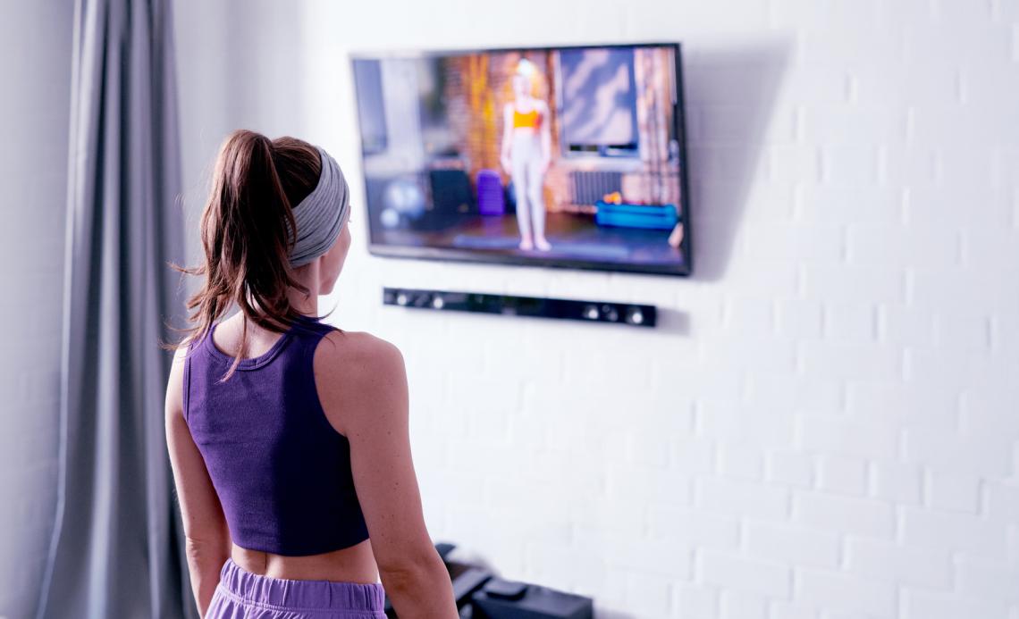 Person following an exercise video on a TV at home.