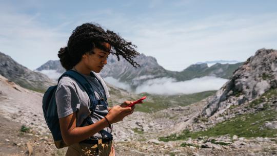 Image of a woman using her mobile phone on the mountains