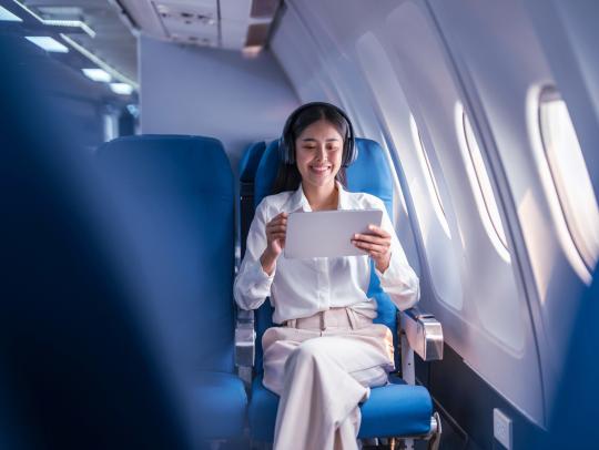 Image of a person using tablet on a flight.