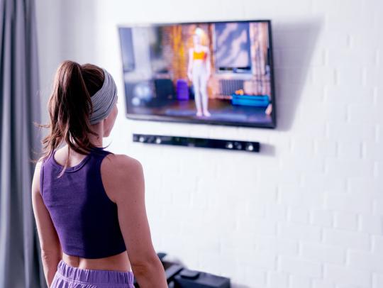Person following an exercise video on a TV at home.