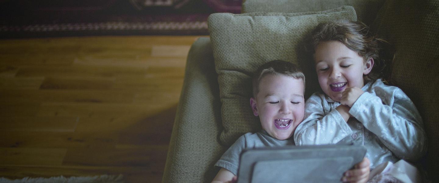 Kids on couch watching tablet 