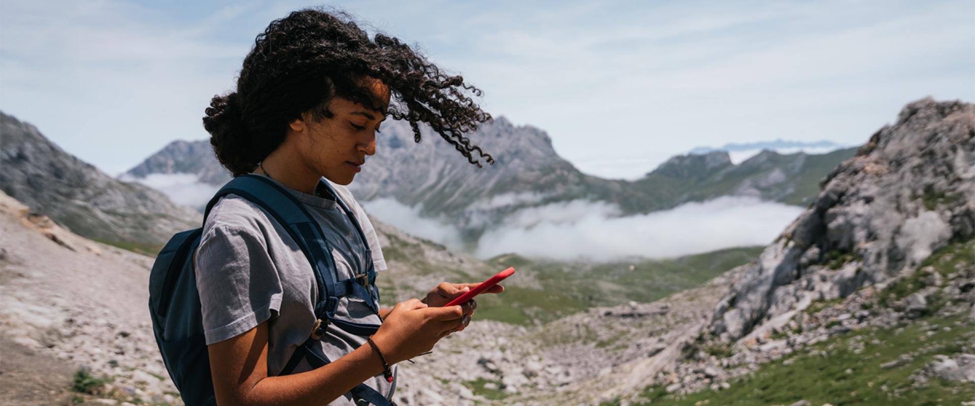 Image of a woman using her mobile phone on the mountains