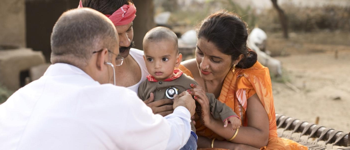 Image of a doctor using a stethoscope to examine a baby held by family