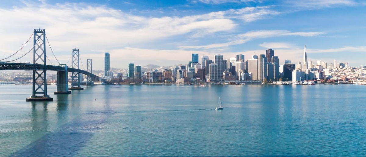 Image of city skyline and bridge overlooking a calm bay.