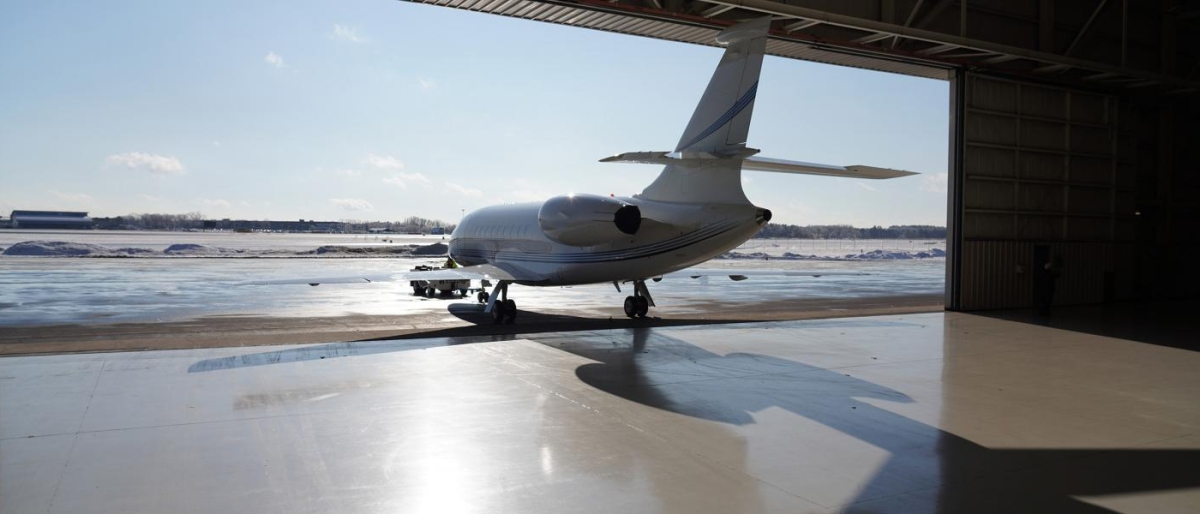 Image of a jet parked at the edge of an aircraft hangar