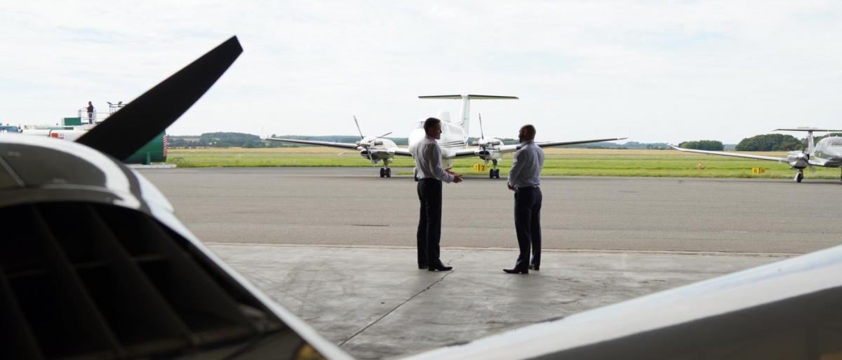 Image of two people standing near aircraft on an airport tarmac.