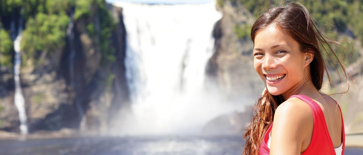 Image of a person standing by a large waterfall.