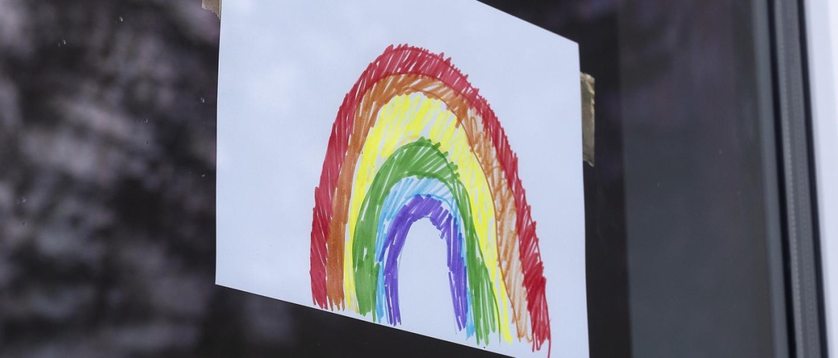 Image of a drawing of a rainbow taped to a window.