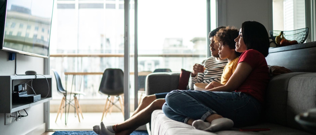Image of an adult and two kids watching television in the living room.