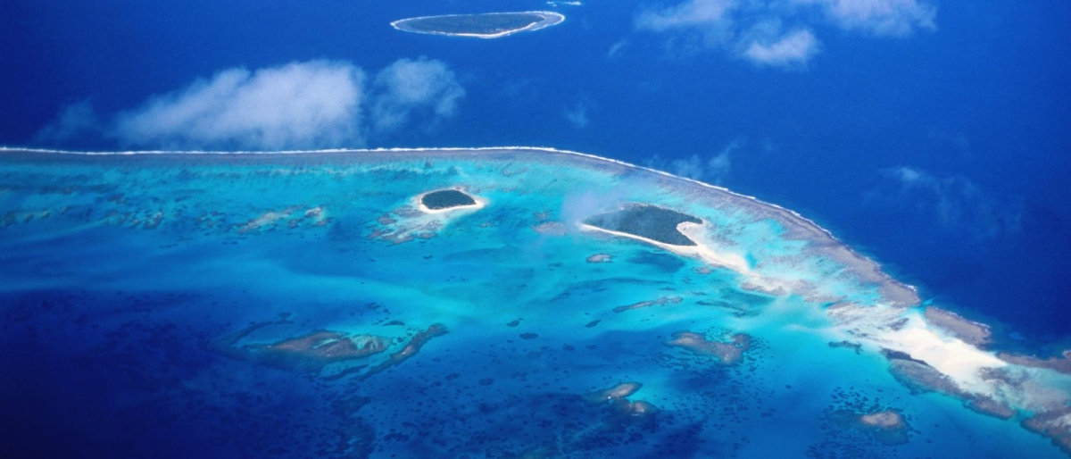 Image of aerial view of a turquoise atoll surrounded by deep blue ocean.