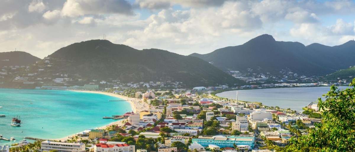 Landscape image of a coastal city with turquoise water, beaches, and mountains in the background