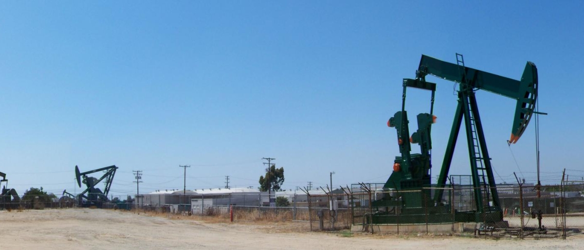 Image of oil pumpjacks operating in a fenced field.