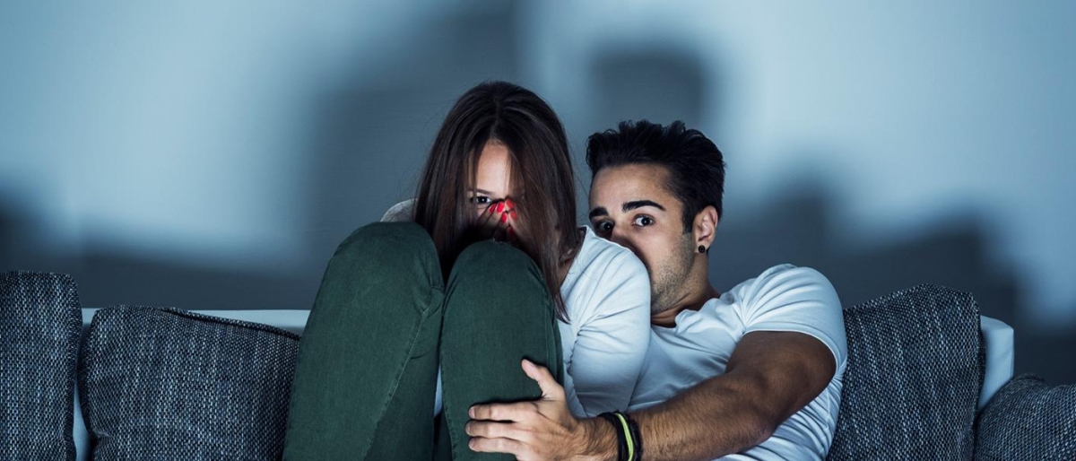 Image of couple sitting on a couch watching television.