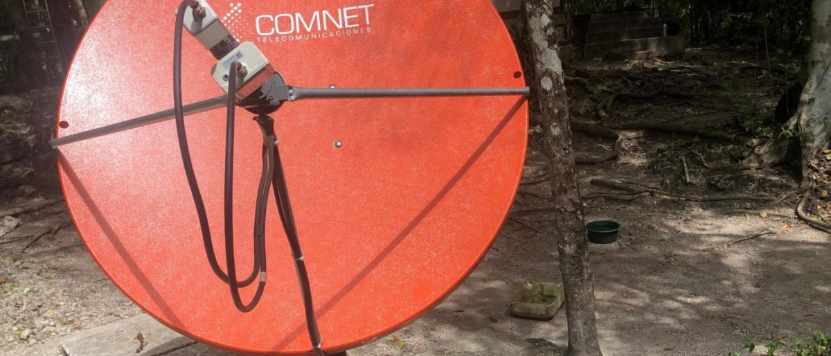 Image of a red COMNET satellite dish mounted outdoors.