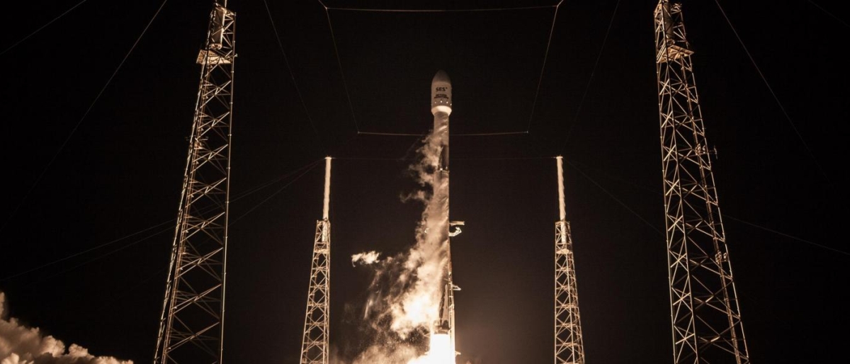 Image of a rocket launching at night from a pad surrounded by tall support towers.