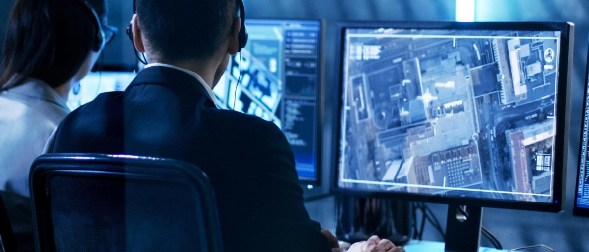 Image of two people reviewing satellite imagery on multiple monitors.