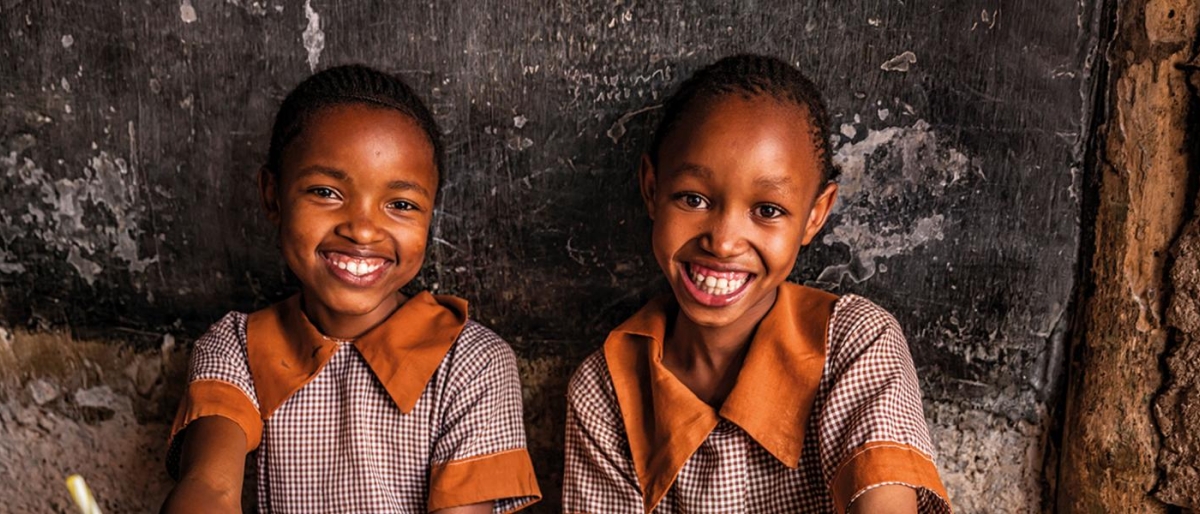 Image of two kids wearing uniforms and looking happy.