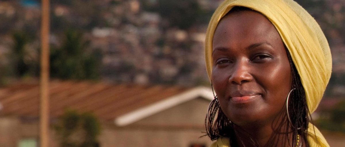 Image of a person wearing a yellow headscarf standing in a village setting.