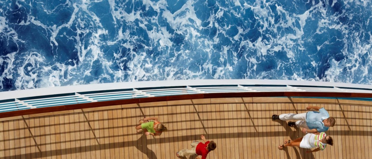 Top‑view image of a cruise ship deck beside deep blue ocean water.