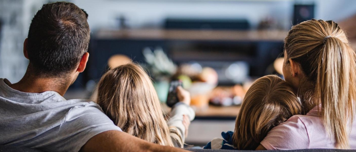 Image of a family sitting together on a couch watching TV.