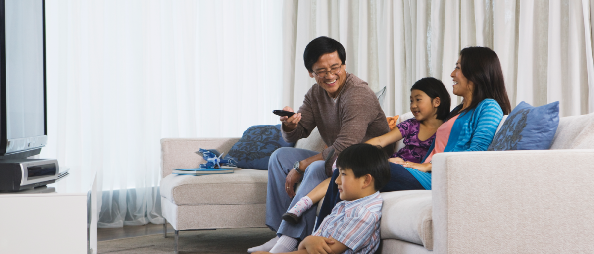 Image of a family chilling on the couch watching TV.