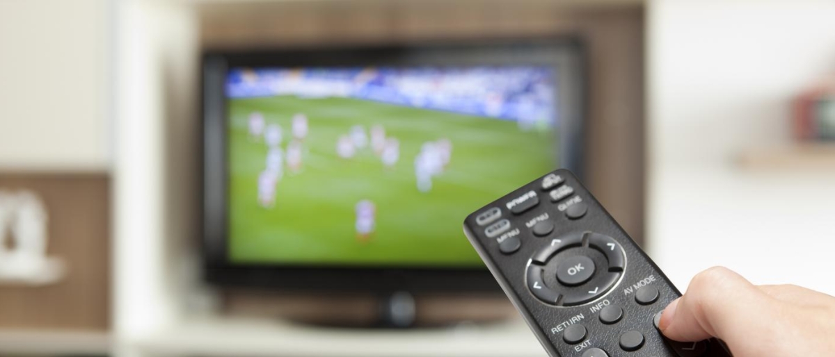 Image of a person's hand holding a remote towards a television.