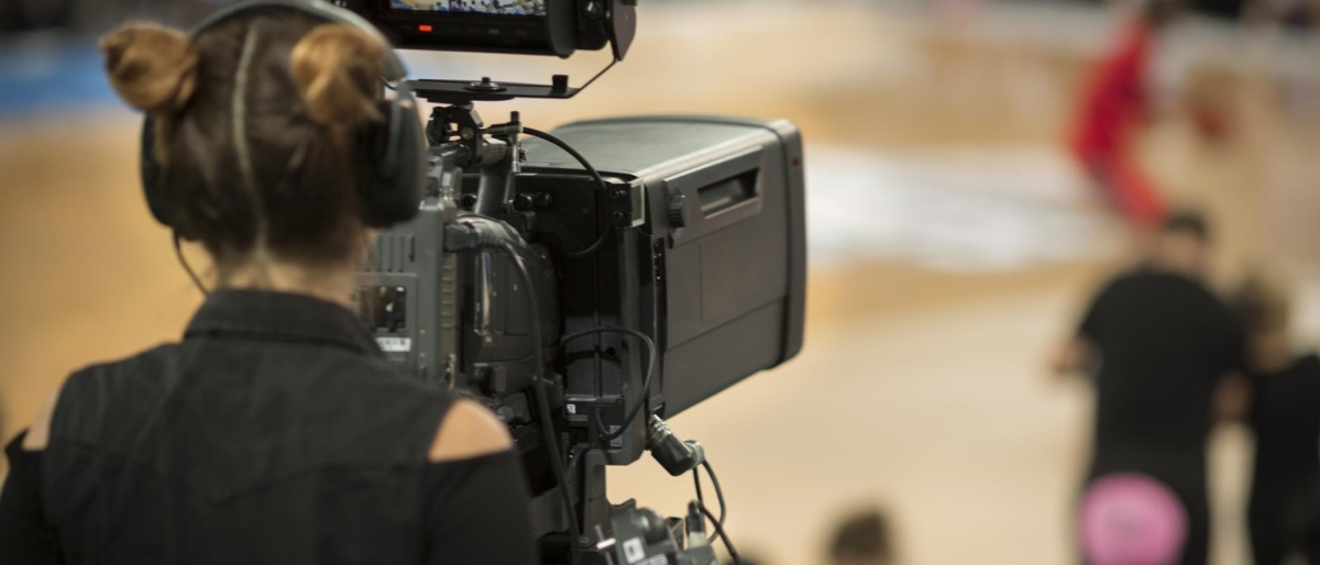 Image of a camera operator filming a sports event with a professional broadcast camera.