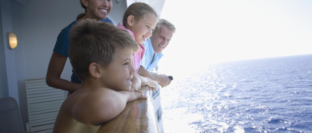 Image of kids and an adult enjoying the sea from a cruise ship.