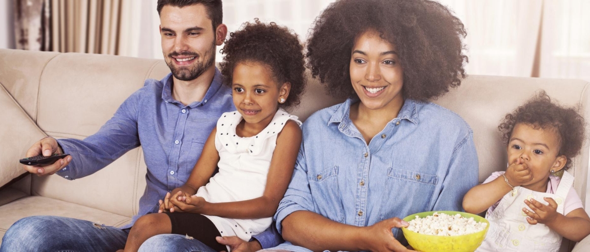 Image of a family sitting on the couch, eating popcorn and watching television.