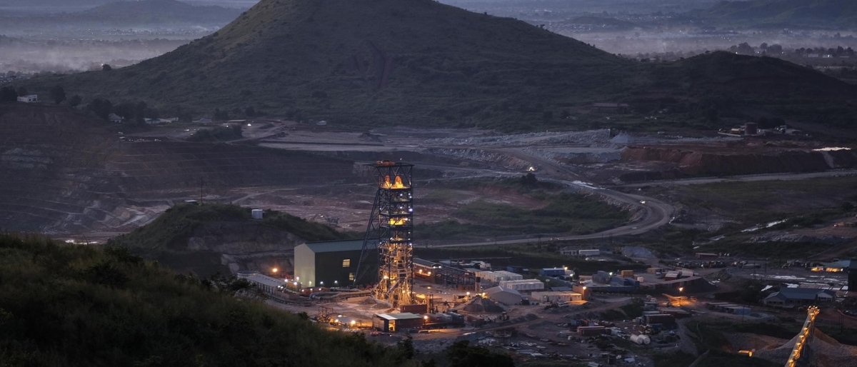Image of illuminated mining site at dusk surrounded by hills.