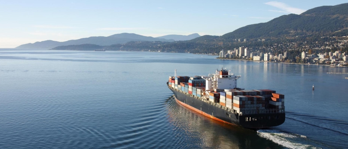 Image of a cargo ship sailing through a coastal bay toward the city.