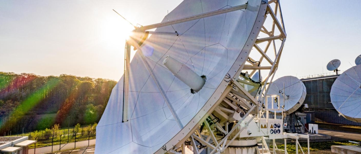 Image of a big antenna dish with sun rays coming through.