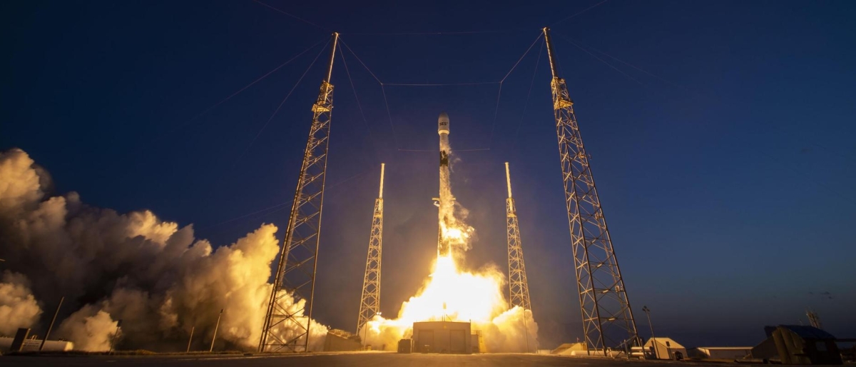 Image of a rocket launching at night with support towers illuminated.