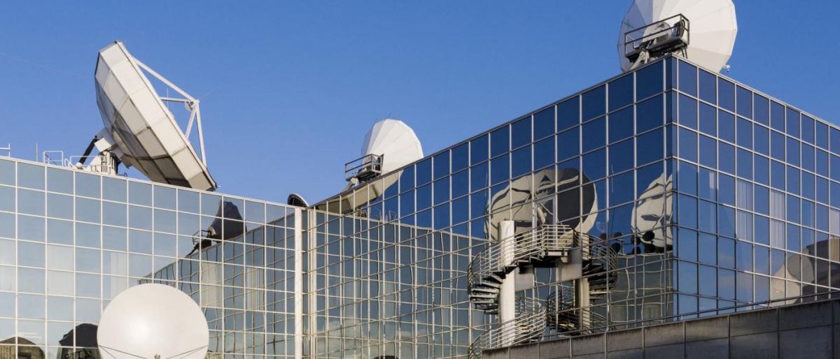 Image of antennas mounted on top of a glass building.