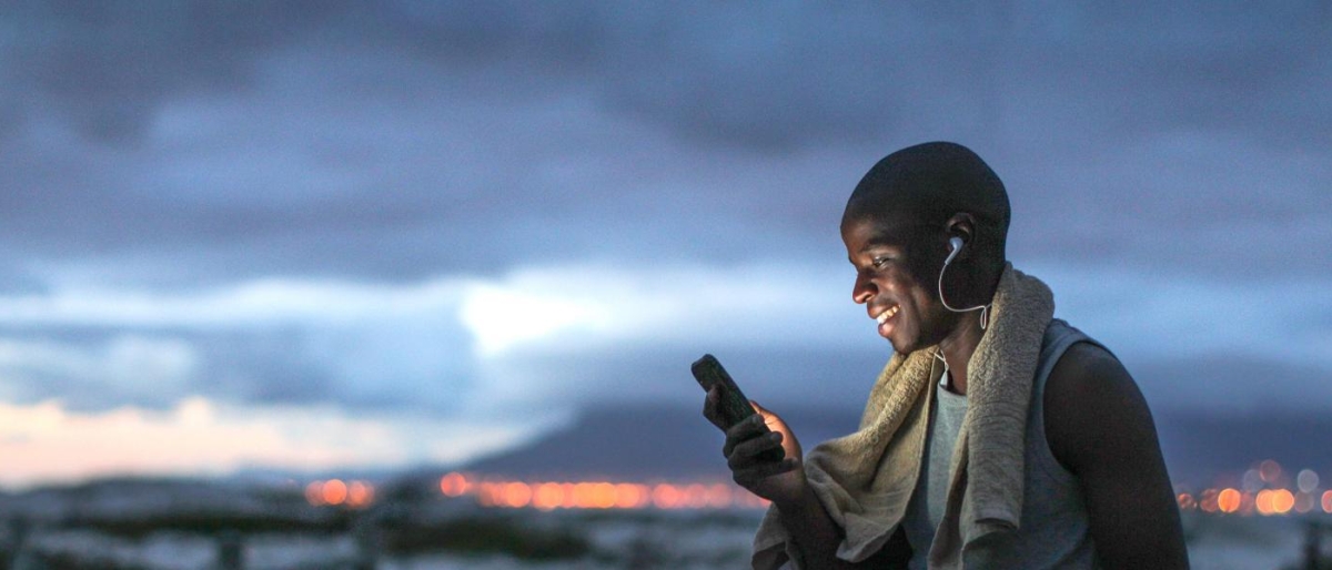 Image of a person using a mobile phone outdoors at dusk.