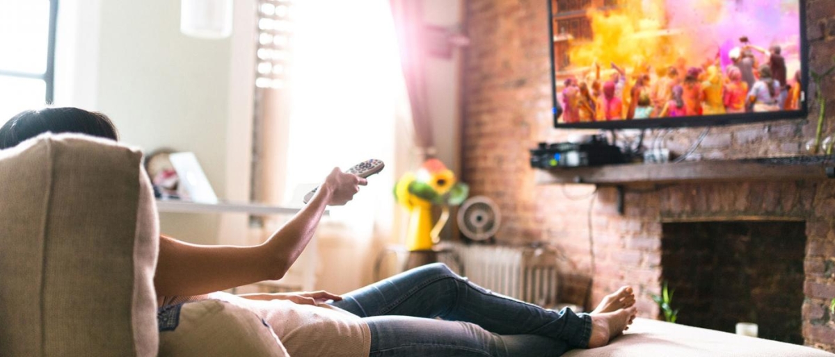Image of a person relaxing on the couch watching television.