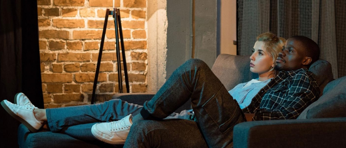 Two people on the couch watching television.