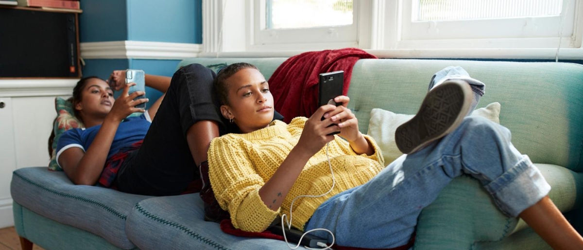 Two people relaxing on the couch using mobile phones.