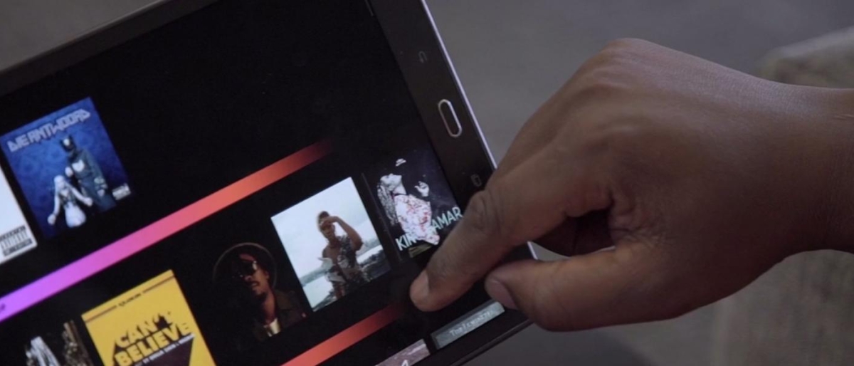 Image of a person swiping on tablet showing different shows