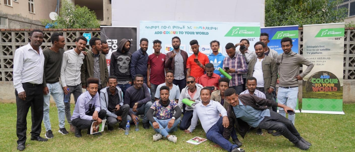 Image of a group of people posing together outdoors in front of event banners.