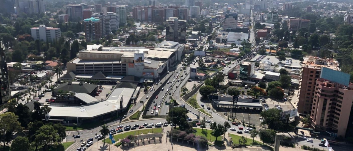 Image of cityscape with busy roads, buildings, and traffic viewed from above