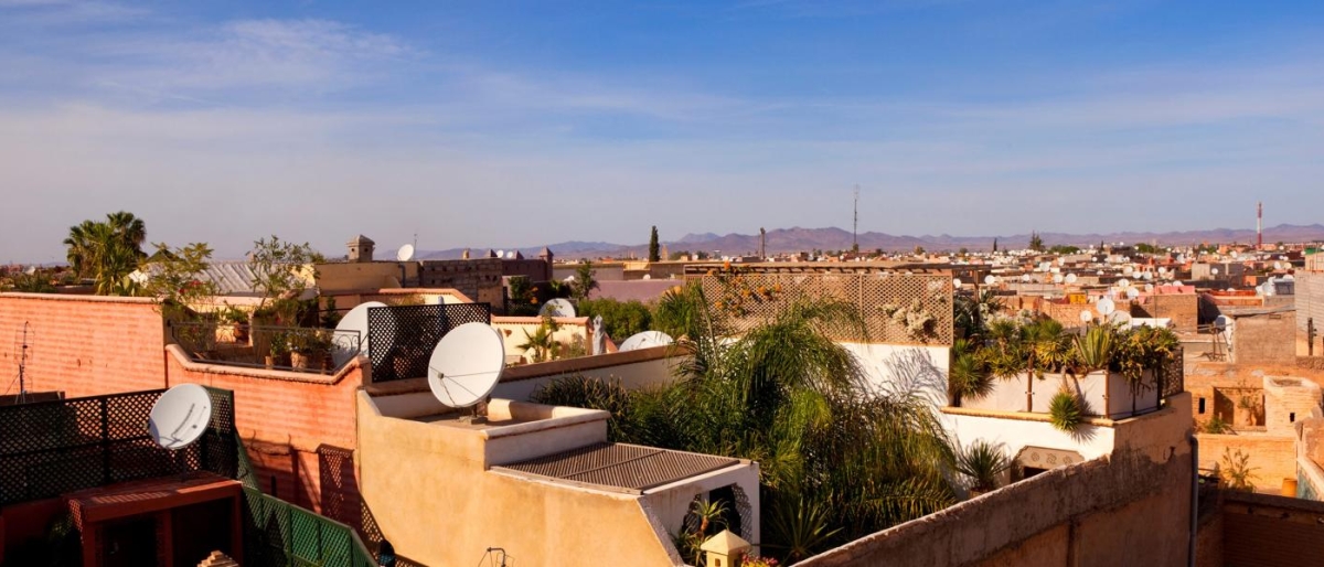 Image of rooftops with satellite dishes in a sunlit cityscape.