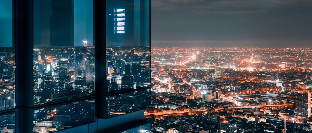 Image of nighttime cityscape with illuminated buildings and reflections in a glass window