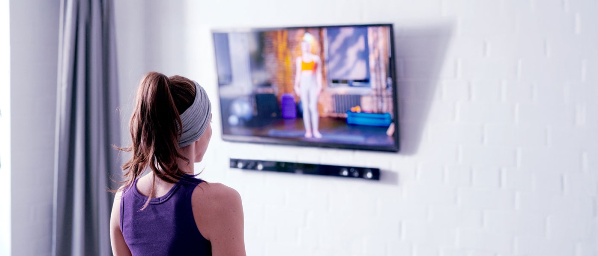Person following an exercise video on a TV at home.